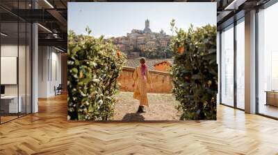 Stylish woman walks on background of cityscape of Siena old town. Concept of travel famous cities in Tosacny region of Italy Wall mural