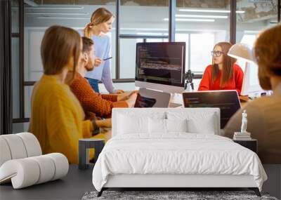 Team of a young programmers dressed casually working on computer code sitting in the modern office interior Wall mural