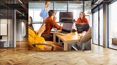 Team of a young programmers dressed casually working on computer code sitting in the modern office interior Wall mural