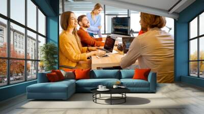 Team of a young programmers dressed casually working on computer code sitting in the modern office interior Wall mural