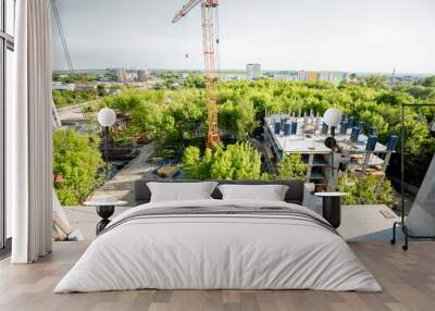 Top view on the construction site of residential buildings on the green area with two workers looking on the construction process Wall mural