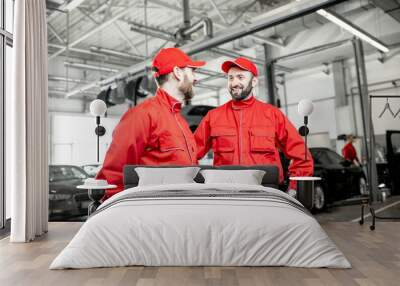 Two auto mechanics in red uniform talking together during the break at the car service Wall mural