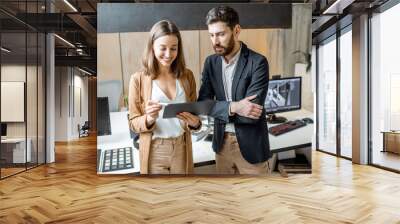 Two creative office employees as an interior designers working with digital tablet, standing together in the modern office of architectural firm Wall mural