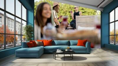 Two stylish carefree persons talk and drink wine at roof top terrace at countryside house. Friends hanging out at picnic outdoors Wall mural