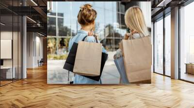 Two women holding empty shopping bags with copy space, while standing back near the shopping mall Wall mural