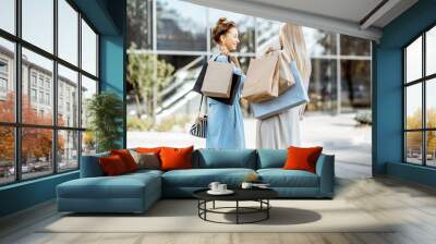 Two women holding empty shopping bags with copy space, while standing back near the shopping mall Wall mural