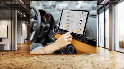 Woman controlling car with a digital dashboard switching autopilot mode, close-up on a touchscreen with launched program. Smart electric car concept Wall mural