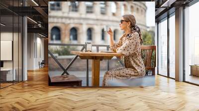 Woman drinking coffee at outdoor cafe near coliseum, the most famous landmark in Rome. Concept of italian lifestyle and traveling Italy. Caucasian woman wearing dress and shawl in hair Wall mural