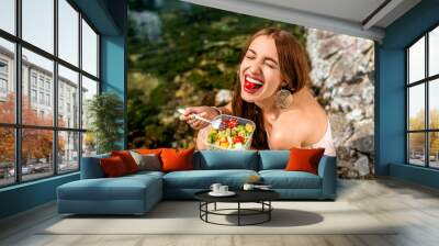 woman eating healthy salad near the river Wall mural