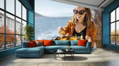 Woman eating paella, traditional spanish dish, while sitting at the restaurant terrace near the ocean. Concept of sea food and good summer vacations Wall mural