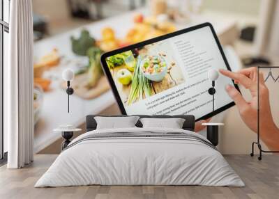 Woman looking on the digital recipe, using touchscreen tablet while cooking healthy meal on the kitchen at home, close-up view on the screen Wall mural