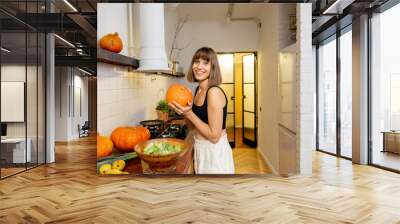 Woman prepares seasonal dish with pumpkins in kitchen Wall mural