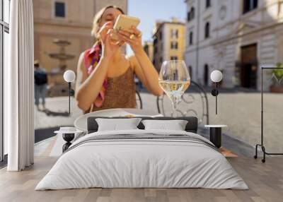 Woman take photo of italian pasta at restaurant on the street in Rome. Concept of Italian gastronomy and food blogging. Stylish woman in dress with colorful hair shawl Wall mural