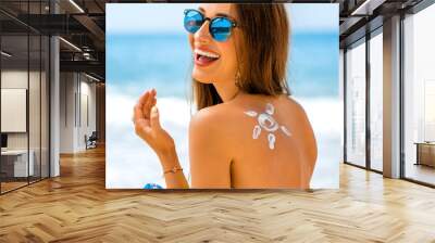 Woman using sun cream on the beach Wall mural