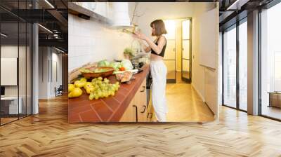 Worried woman has a problem preparing food, having burnt meal on kitchen hob. Confused housewife waves her hands in the smoke. Food ingredients on table top in front Wall mural