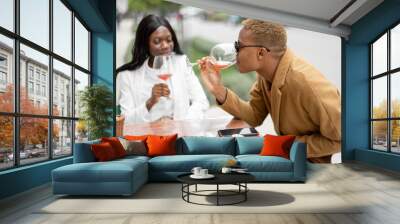 Young african woman and latin man having fun during a business lunch at outdoor cafe. Concept of teambuilding and corporate event. Idea of rest and leisure on job Wall mural