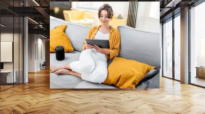 young and cheerful woman using a digital tablet while sitting relaxed on the couch at home. concept  Wall mural