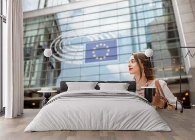 Young businesswoman standing with phone near the Parliament building of European Union in Brussel city Wall mural