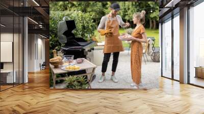 Young couple have fun while cooking vegetables on grill at backyard on nature. Eating and spending summertime at garden of country house Wall mural