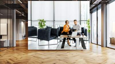 young couple sitting on the comfortable sofa at the bank or financial institution office, solving so Wall mural