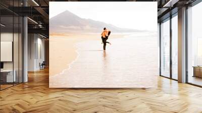 Young couple with naked torso embracing on the beautiful sandy beach with mountains on background on Fuerteventura island in Spain. General plan with copy space Wall mural