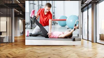 Young girl exercising on the decompression simulators with trainer during the spine treatment at the rehabilitation gym Wall mural