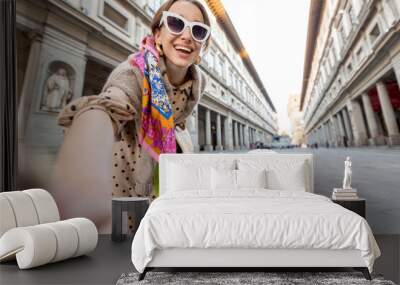 Young happy woman takes selfie with a dog on Uffizi square visiting museum in famous italian city Florence. Female tourist traveling italian landmarks Wall mural