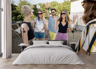 Young stylish friends greets each other tightly while gathering on a party outdoors. Two hipsters meet on rooftop party Wall mural