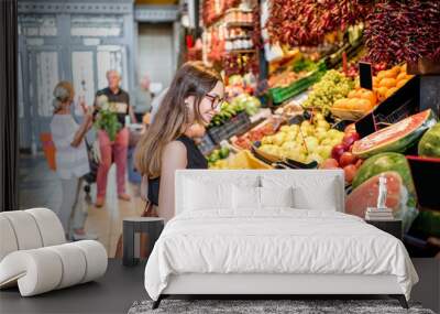 Young woman choosing goods standing at the counter with a bunch of different fresh food in theGreat Market hall in Budapest Wall mural