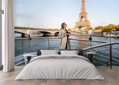 Young woman enjoying beautiful landscape view on the riverside with Eiffel tower from the boat during the sunset in Paris Wall mural