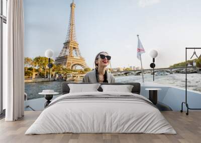 Young woman enjoying beautiful landscape view on the riverside with Eiffel tower from the boat during the sunset in Paris Wall mural