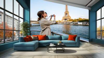 Young woman enjoying beautiful landscape view on the riverside with Eiffel tower from the boat during the sunset in Paris Wall mural