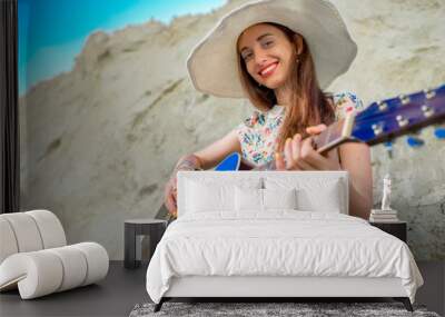 Young woman playing acoustic guitar sitting on the sand Wall mural