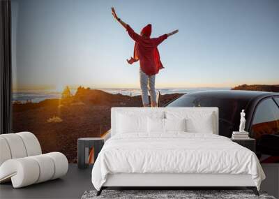 Young woman rocky landscapes above the clouds, standing on the car highly in the mountains. Carefree lifestyle and travel concept Wall mural