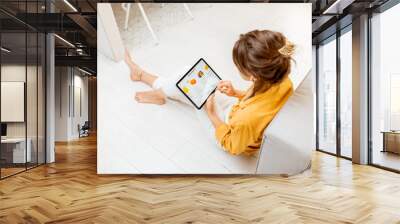 Young woman shopping fresh food online using a digital tablet, while sitting on the floor at home. Concept of buying online using mobile devices Wall mural