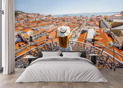 Young woman tourist enjoying beautiful cityscape top view on the old town during the sunny day in Lisbon city, Portugal Wall mural