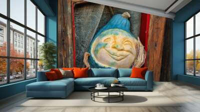 Carved blue pumpkin with a happy face looking out of a window with a wooden frame Wall mural