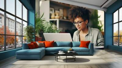 Beautiful African American woman in glasses studying or working at home using a laptop Wall mural