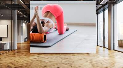 Motivated sporty woman training on mat indoor winter day, using foam roller massager for relaxation, stretching spine muscles, doing fascia exercise. Wall mural