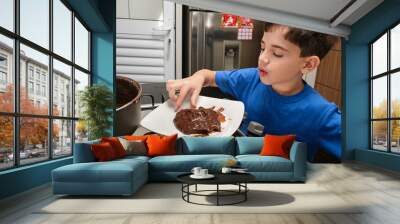 8 year old child picking up the brigadeiro, a Brazilian sweet, with his fingers. Wall mural