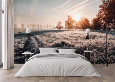 Calm and wonderful peaceful winter morning with frozen grass meadow and white nature and colorful ealry morning sunrise tones. Frosty white winter wonderland in the countryside with shadows Wall mural