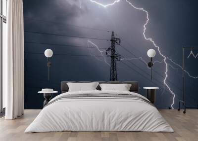 Lightning striking above a transmission tower on a dark gloomy and cloudy evening Wall mural