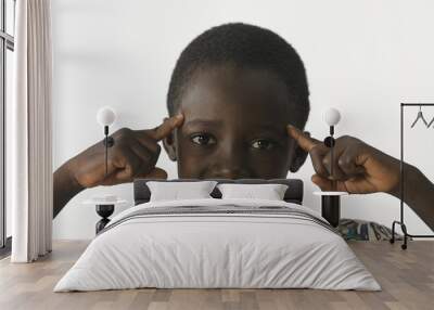 African ethnicity boy thinking with his fingers pointing to his head, isolated on white Wall mural