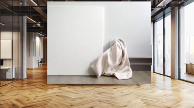 art canvas in a horizontal position on the floor leaning against a white wall clean cloth for mockup art presentation Wall mural