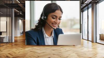 Happy Indian call center agent wearing headset talking to client working in customer support office. Professional contract service telemarketing operator using laptop having conversation. Wall mural