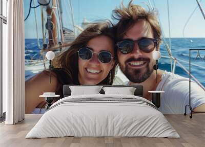 A man and a woman are smiling while taking a selfie on a sailboat in the ocean. The blue sky and water make the perfect backdrop for their travel photograph Wall mural