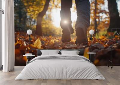 Close-up of a man walking on fallen autumn leaves in the forest during a sunny day in autumn. Wall mural