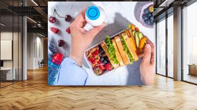 Back to school. Mother female hands making kids school lunch box with fresh fruits, berry, yogurt, healthy sandwich, vegetable snacks. White kitchen marble table copy Wall mural