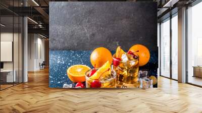 Classic alcohol cocktail, whiskey with ice cubes, orange slices and cocktail red cherries. In two glasses, on a dark blue concrete table, Wall mural