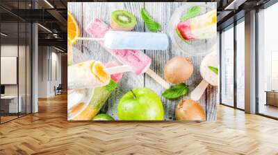 Colorful fruit ice cream popsicle. Juicy gelato lollypops on sticks, with different fresh tropic fruits, wooden background copy space Wall mural